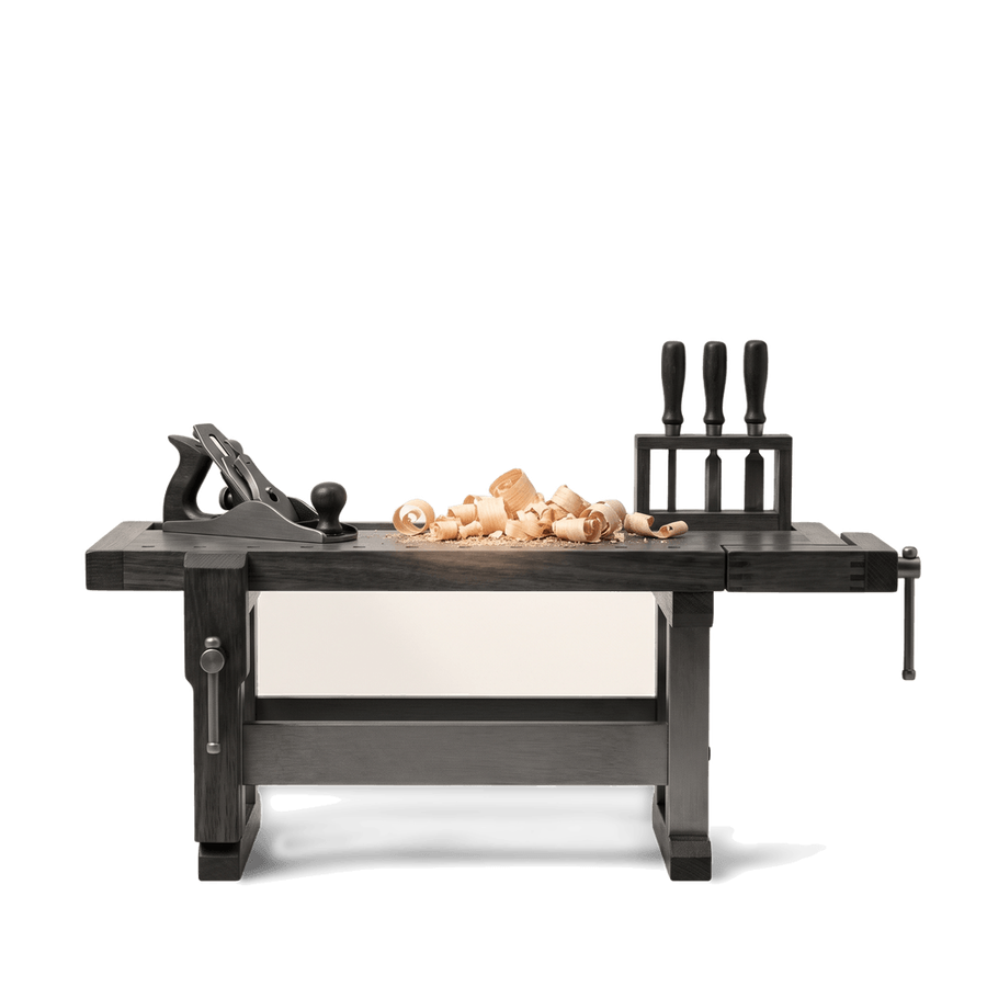 A joinery workbench with a plane, chisels and shavings, in black and white