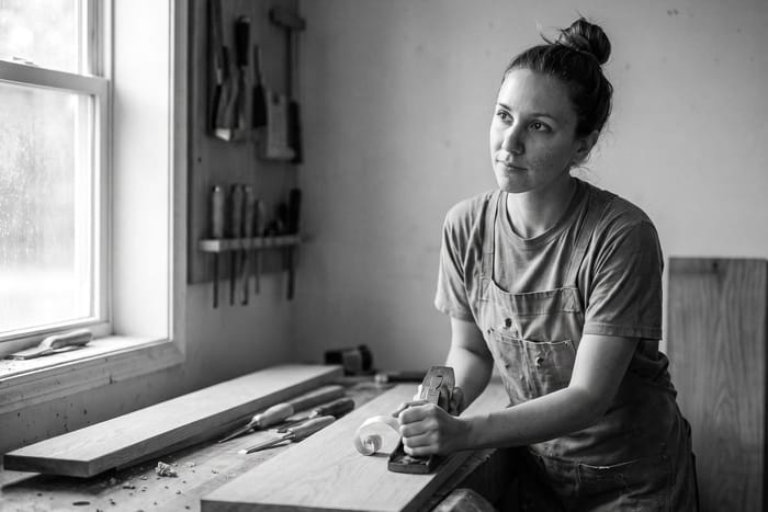 Nell in her joinery workshop, planing oak, in black and white