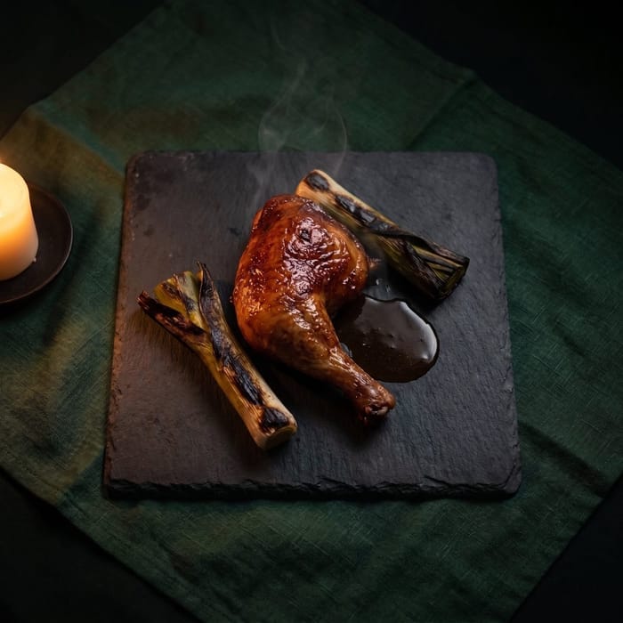 Roast chicken on a slate plate by candlelight